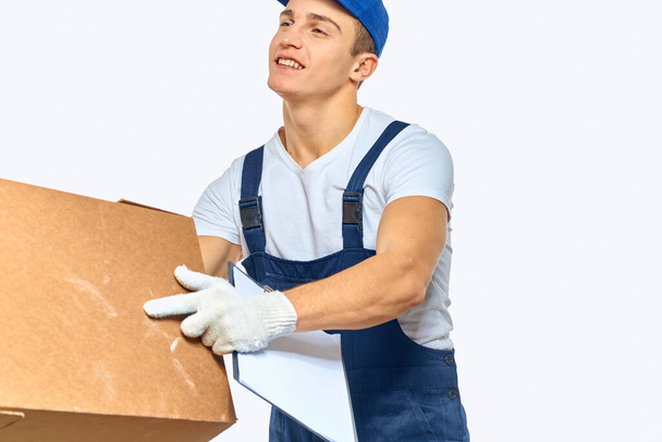 Man worker with box in hands delivery loading service work light background - Photo, Image