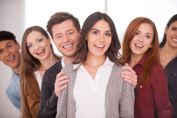 Woman smiling while group of cheerful young people standing behind her - Foto, Imagen