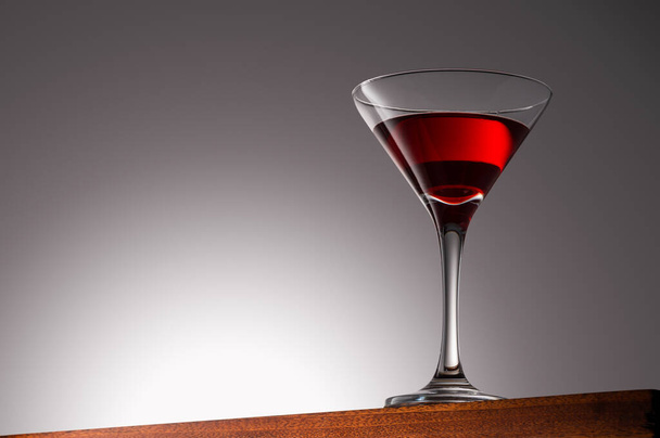 Boisson rouge en verre Martini sur une surface en bois avec fond dégradé avec chemin de coupe - Photo, image