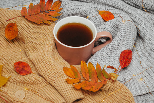 autumn, dry red autumn leaves lie on sweaters that are stacked around a hot espresso mug, around lies a led garland, Flatley - Zdjęcie, obraz