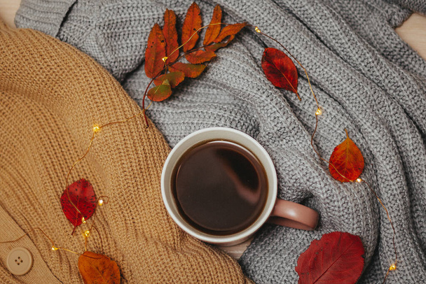 autumn, dry red autumn leaves lie on sweaters that are stacked around a hot espresso mug, around lies a led garland, Flatley - Fotó, kép