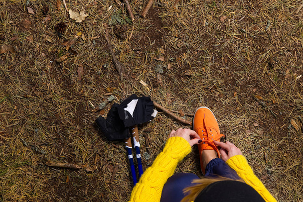 Deportiva mujer de senderismo atando cordones de zapatos en sus zapatos de correr mientras toma un descanso después de caminar en el bosque de otoño. concepto de senderismo, estilo de vida saludable al aire libre. - Foto, imagen