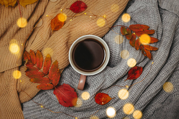 autumn, dry red autumn leaves lie on sweaters that are stacked around a hot espresso mug, around lies a led garland, Flatley - Fotó, kép