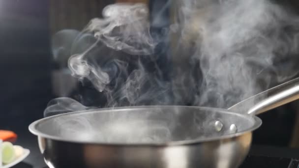 White smoke in slow motion rising above hot frying pan on black background. Cooking in restaurant. Delicious risotto being cooked in restaurant kitchen. Full hd - Footage, Video