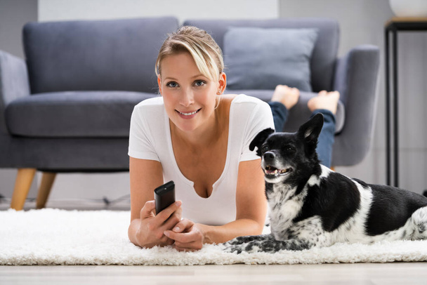 Γυναίκα βλέποντας τηλεόραση στο σπίτι με το σκυλί - Φωτογραφία, εικόνα