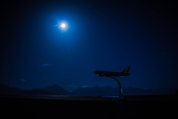 Vliegtuigmodel op de achtergrond van de nachtelijke skyline in de stad. Almaty. - Foto, afbeelding