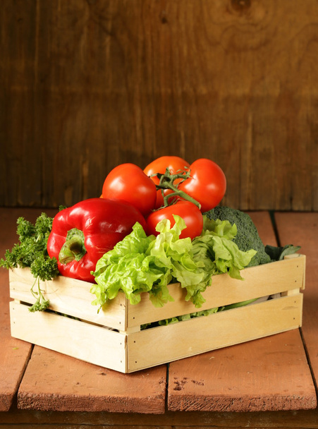 Various vegetables in a wooden box (tomatoes, cucumbers, lettuce) - Photo, Image