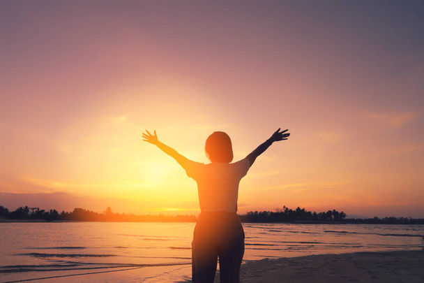 Kopieer ruimte van de vrouw opstaan hand op zonsondergang hemel op het strand en eiland achtergrond. Vrijheid en reizen avontuur concept. Vintage Toon filter effect kleur stijl. - Foto, afbeelding