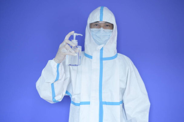 An Asian man is wearing ppe suit on purple background . - Photo, image