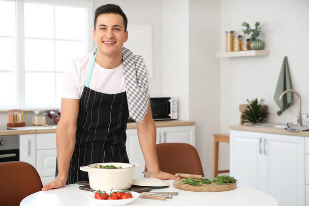 Jeune homme avec de savoureux aliments cuits dans la cuisine - Photo, image