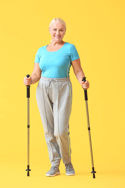 Donna matura con bastoni da passeggio su sfondo di colore - Foto, immagini