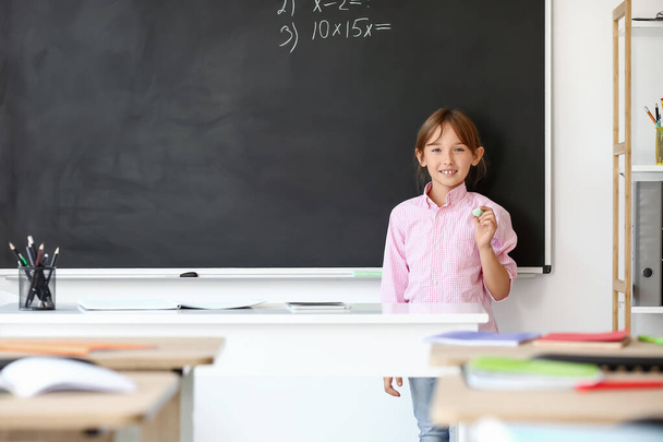 Cute little schoolgirl near blackboard in classroom - Foto, Bild