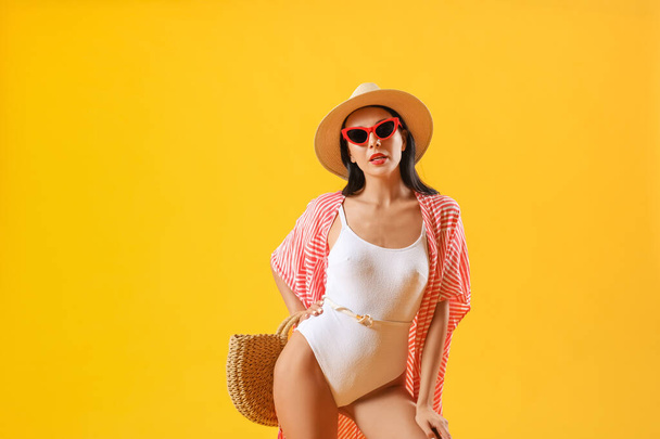 Belle jeune femme en tenue de plage sur fond de couleur - Photo, image