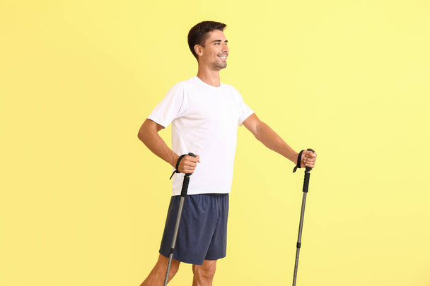 Giovane uomo con bastoni da passeggio su sfondo di colore - Foto, immagini