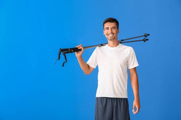 Young man with walking poles on color background - Fotó, kép