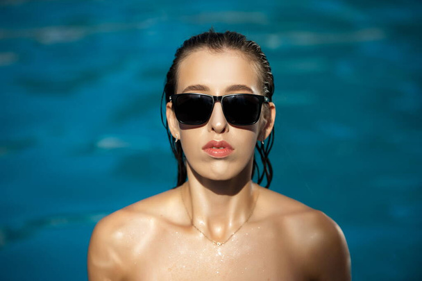Portrait of a beautiful woman against the background of blue water, close-up - Фото, изображение