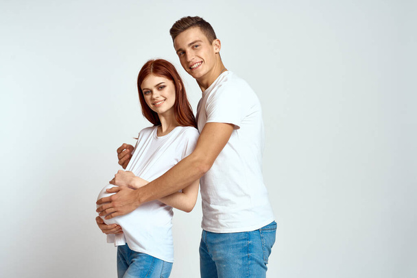 una mujer embarazada y un hombre joven están esperando a un bebé en un fondo de luz emociones amor familiar - Foto, imagen