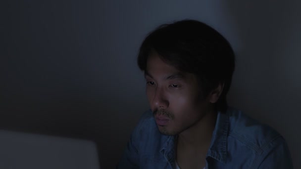 Азиатский случайный бизнесмен или фрилансер в джинсовой рубашке, печатающий ноутбук Touch Chin и работающий допоздна в офисе - Кадры, видео
