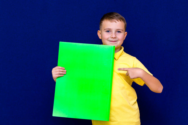 Happy nice kaukaskie dziecko wskazując palcem na informacje reklamowe na niebieskim tle - Zdjęcie, obraz
