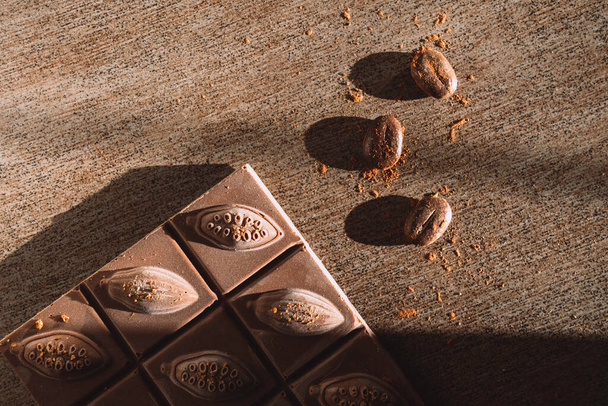 chocoladereep met bonen in trendy zonnige schaduwen, rijk aan energie en antioxidanten, selectieve focus, kopieerruimte - Foto, afbeelding