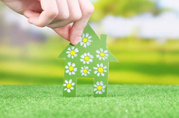 Little paper house in hand on green grass on bright background - Photo, Image