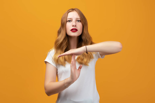 Pretty Young woman wearing white t shirt Doing time out gesture with hands, frustrated and serious face. Studio shot, yellow background - Photo, Image