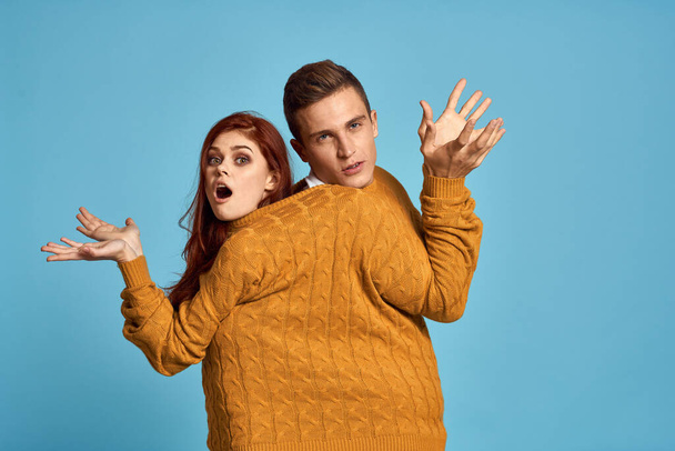 Paar in gelbem Pullover posiert vor blauem Hintergrund - Foto, Bild