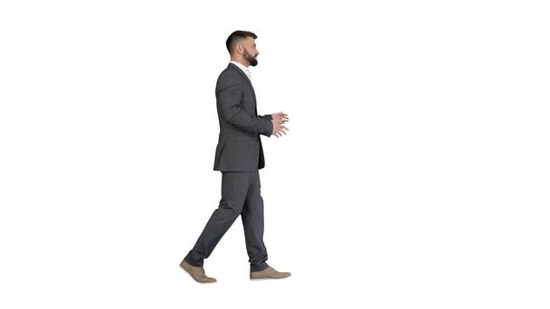 Bearded businessman walking and explaining something on white ba - Фото, зображення
