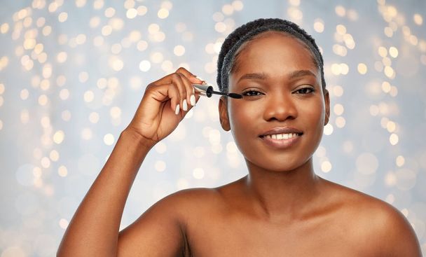 beautiful african american woman applying mascara - Fotó, kép