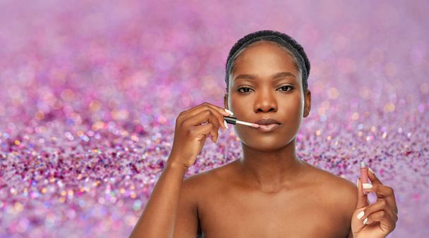 african american woman applying lip gloss - Foto, immagini