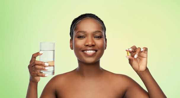 african woman with cod liver oil and water glass - Foto, Imagen