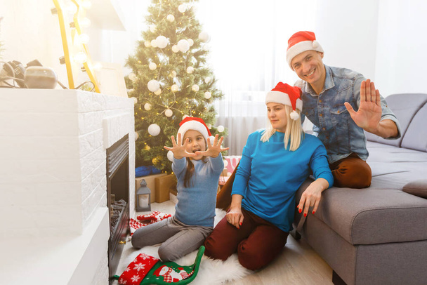 щаслива молода сім'я з однією дитиною тримає різдвяний подарунок і посміхається
 - Фото, зображення