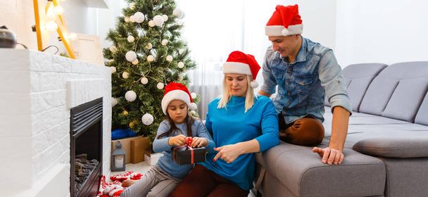 Молода сім'я на різдвяний ранок обмінюється подарунками і насолоджується разом
. - Фото, зображення