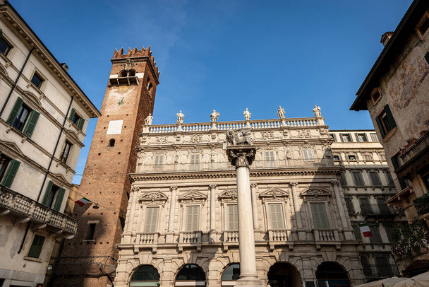 Βερόνα, Piazza delle Erbe. Αρχαίο ανάκτορο των Μπαρόκ 1626-1663, μεσαιωνικός πύργος Γκαρντέλο (XII αιώνας), και το φτερωτό λιοντάρι του Αγίου Μάρκου σύμβολο της Ενετικής Δημοκρατίας και του Ευαγγελιστή Μάρκου. Veneto, Ιταλία, Ευρώπη. - Φωτογραφία, εικόνα
