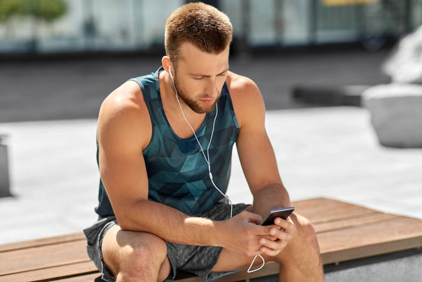 fiatal sportoló férfi fülhallgatóval és okostelefonnal - Fotó, kép