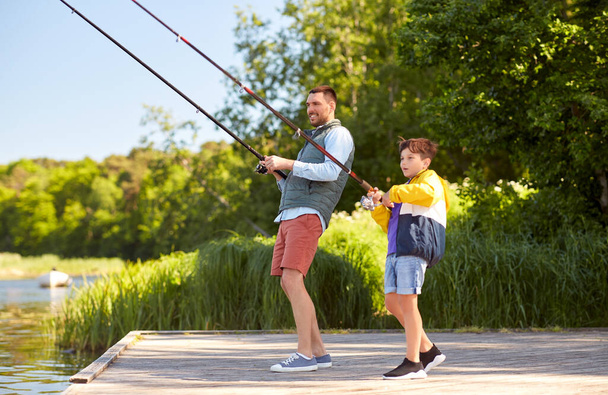 happy smiling father and son fishing on river - Foto, Imagen