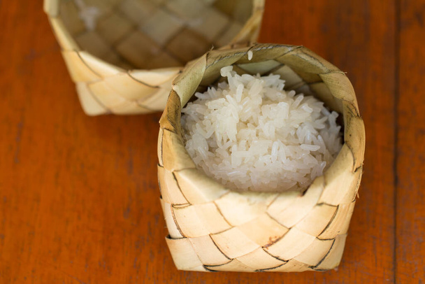 Липкий рис (глютиновый рис) в сухом сосуде из пальмовых листьев (кратип). Стиклый рис - популярный вид риса в Таиланде с натуральной упаковкой. - Фото, изображение