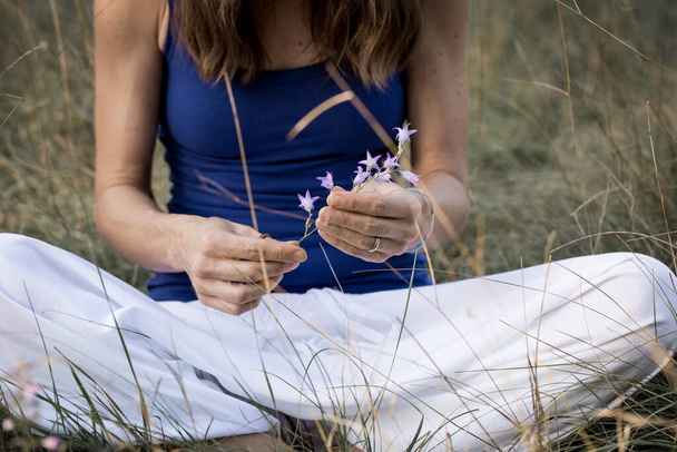 Nahaufnahme weiblicher Hände, die sanft eine zerbrechliche wilde Blume halten - Foto, Bild