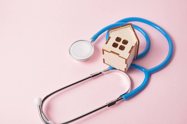 Medical stethoscope and toy house on a pink background with copy space - Valokuva, kuva