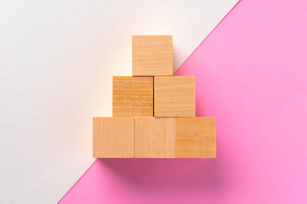 Wooden square block on pink and white background - Valokuva, kuva