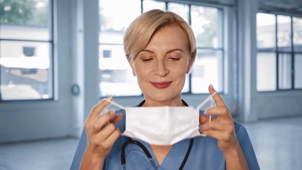 feliz médico de mediana edad quitándose la máscara médica  - Metraje, vídeo