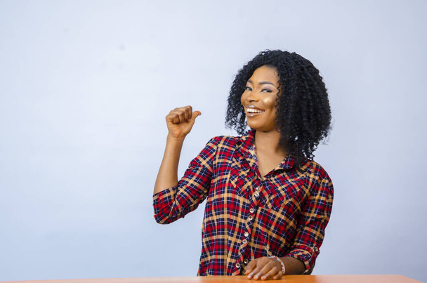 A cheerful African female pointing on her side with her finger - Photo, Image