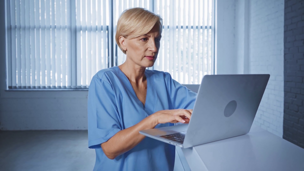 blonde et d âge moyen médecin en utilisant un ordinateur portable dans la clinique  - Séquence, vidéo