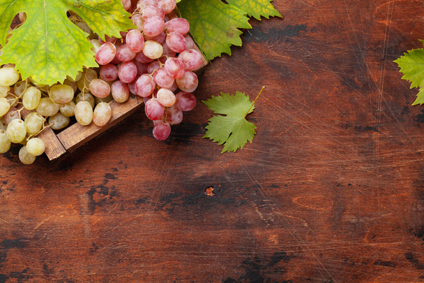 Grapes and autumn leaves on wooden table. Top view flat lay with copy space - Photo, Image