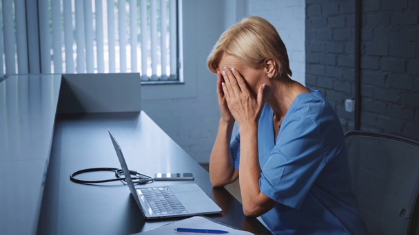 boos en middelbare leeftijd arts typen op laptop op het bureau - Video