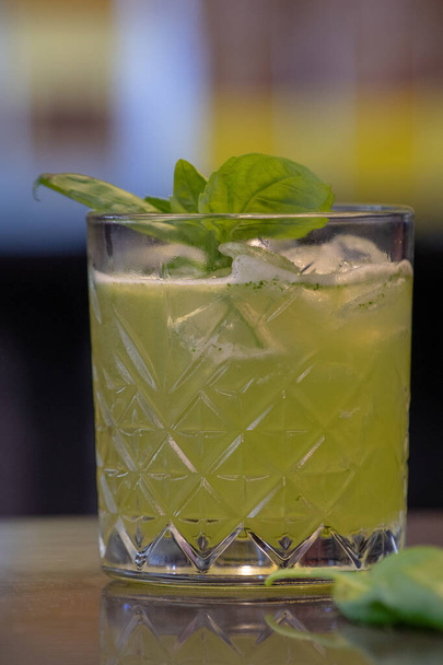 A closeup shot of a glass of iced cocktail with mint on a bar counter - Fotografie, Obrázek