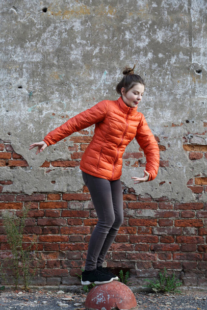 Funny active teen gitl against red brick wall outdoor. Selected focus. - Foto, immagini
