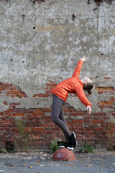 Funny active teen gitl against red brick wall outdoor. Selected focus. - Fotó, kép