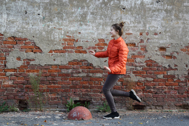 Funny active teen gitl against red brick wall outdoor. Selected focus. - Foto, Bild