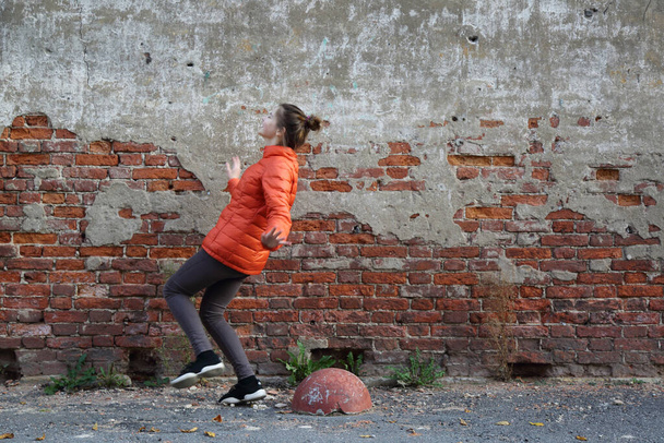Funny active teen gitl against red brick wall outdoor. Selected focus. - Φωτογραφία, εικόνα